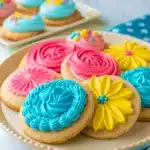 Plate of elaborately frosted sugar cookies shaped like flowers and roses in blue, yellow, and pink.