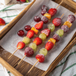 Tanghulu skewers with strawberries and grapes on parchment