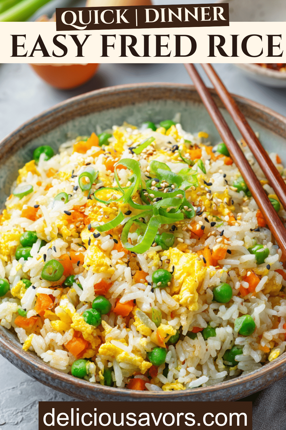 Large bowl of colorful, homemade family fried rice with peas, carrots, scrambled egg, and scallions on a kitchen table.