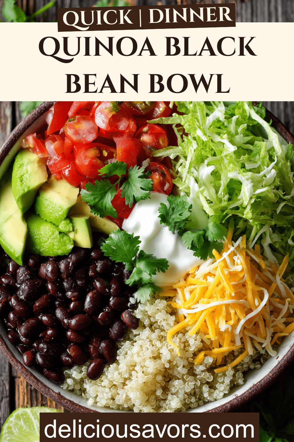 Overhead view of a colorful Quinoa Black Bean Bowl with fresh toppings including avocado, cheese, lettuce, tomatoes, sour cream, and cilantro on a rustic wooden table
