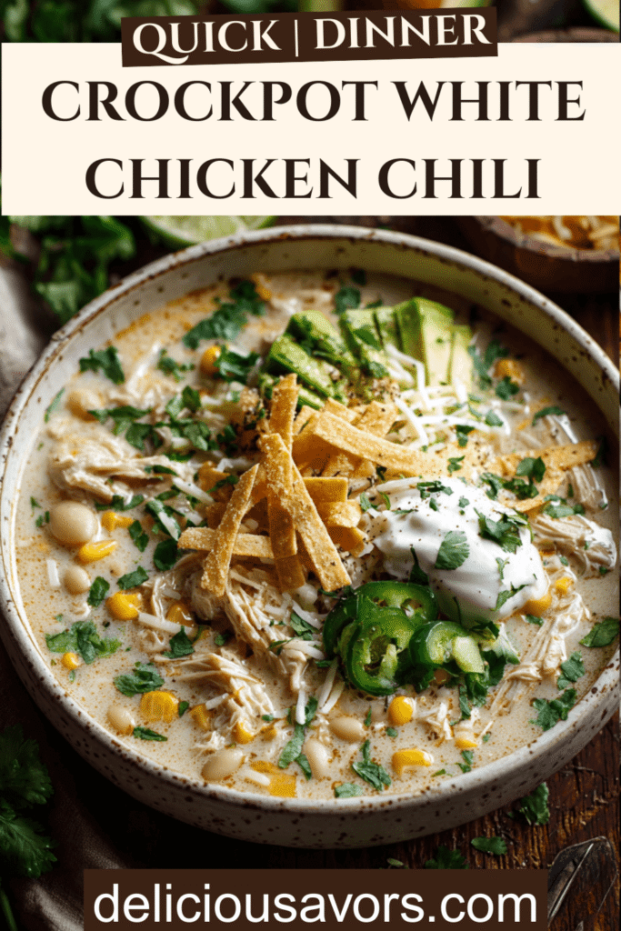 Creamy Crockpot White Chicken Chili in rustic bowl topped with avocado, jalapeños, cilantro, sour cream, cheese and tortilla strips on wooden table