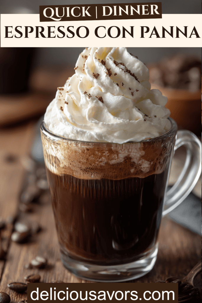 Close-up of an espresso con panna in a small glass cup topped with whipped cream on a wooden table with coffee beans scattered around.