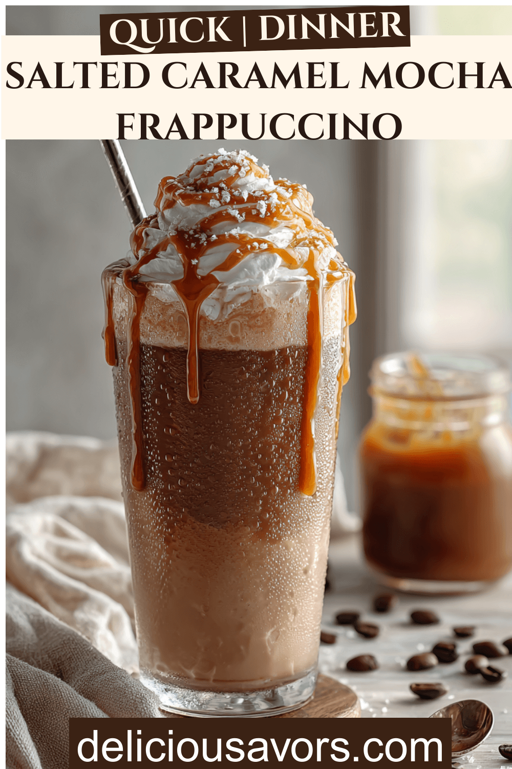 Iced salted caramel mocha frappuccino in a tall glass topped with salted caramel cream cold foam and caramel drizzle on a light wooden table.