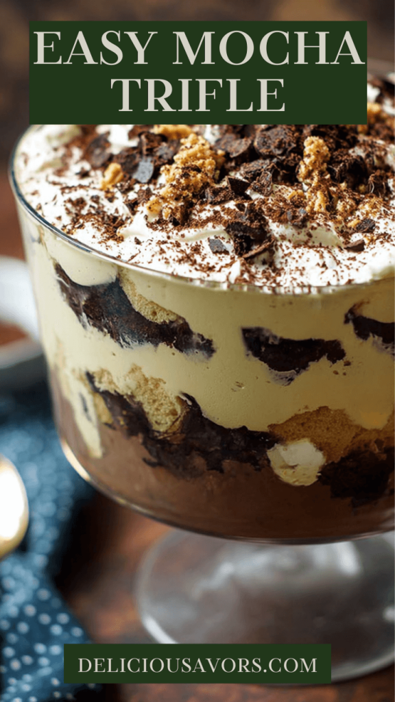 Layered mocha trifle dessert in clear glass bowl showing chocolate cake, coffee pudding, and whipped cream layers topped with crushed biscotti.